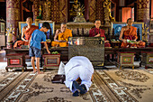 Persons praying, Monks statue, in Wat Phra Singh temple, Chiang Mai, Thailand