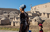 Mother and daughter walking in front of Old cemetery at the city wall, old city, Khiva, Uzbekistan
