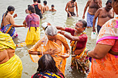 women and men praying and bathing, in the ghats of Ganges river, Varanasi, Uttar Pradesh, India.