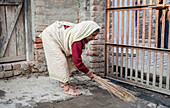 Witwe beim Reinigen ihres Ashrams, Vrindavan, Mathura-Distrikt, Indien