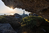 Punta Nariga lighthouse at sunset from a cave, Costa da Morte, Galicia, Spain, Iberian Peninsula, Western Europe