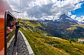 Ein Tourist beobachtet das Matterhorn aus dem Zug der Gornergratbahn, Zermatt, Kanton Wallis, Visp, Schweiz, Westeuropa