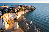 Aerial view of Pizzomunno beach and the white stack with Vieste peninsula in the background. Foggia province, Gargano National Park, Apulia, Italy.