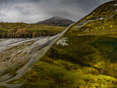 Splitaufnahme des Flusses Kinglas mit Hügeln im Hintergrund. Algen sind unter dem Wasser sichtbar. Schottland.