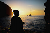 Silhouette einer jungen Frau, die einen Sonnenuntergang an einem schönen Strand genießt