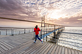 Morgenlauf nahe der Vasco-Da-Gama-Brücke bei Sonnenaufgang, Lissabon, Portugal