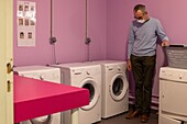 Resident in the laundry room doing his laundry, care home for adults with mental disabilities, residence la charentonne, adapei27, association departementale d'amis et de parents, bernay, eure, normandy, france