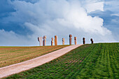 Blick auf den Hügel des Standorts der Steinstatuen von Dodekalitten mit Feldern und einer kleinen Landstraße, Insel Lolland, Seeland, Dänemark, Europa