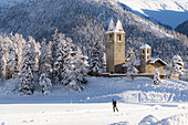 Man enjoying cross-country ski in the snowy fields at feet of San Gian church, Celerina, Graubunden, Engadin, Switzerland