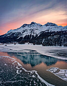 Winter sunrise on snowcapped mountains reflected in frozen Lake Silvaplana, Maloja, Engadine, Graubunden canton, Switzerland