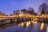 Illuminated buildings and bridge reflected in Keizersgracht canal, Amsterdam, North Holland, The Netherlands