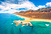 Aerial view of El Islote islet in the turquoise sea along the desert Cofete beach, Jandia, Fuerteventura, Canary Islands, Spain