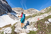 Hiker walking on mountain path to rifugio Pian di Cengia hut, Tre Cime nature park, Sesto Dolomites, South Tyrol, Italy