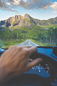 Personal perspective of person driving on road towards mountains in Senja, Troms county, Norway