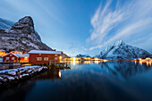 Winter dusk over snowcapped mountains and fishing village of Reine, Nordland county, Lofoten Islands, Norway