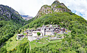 Small alpine village at feet of majestic mountains in summer, Savogno, Valchiavenna, Valtellina, Lombardy, Italy