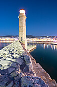 Beleuchteter Leuchtturm in der Abenddämmerung im alten venezianischen Hafen von Rethymno, Insel Kreta, Griechenland
