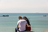 Young couple sitting over the sea on the beach of boulogne sur mer, (62) pas-de-calais, france