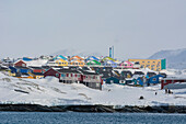 Colorful houses by the sea, in a snowy landscape. Disko Bay, Ilulissat, Greenland.