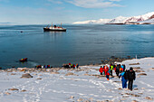 Expedition cruise ship tourists explore the Bockfjorden's shore. Bockfjorden, Spitsbergen Island, Svalbard, Norway.