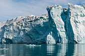 The massive walls of Lilliehook Glacier reflect on arctic waters. Lilliehookfjorden, Spitsbergen Island, Svalbard, Norway.