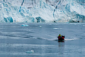A zodiac boat with ecotourists navigates near Lilliehook Glacier. Lilliehookfjorden, Spitsbergen Island, Svalbard, Norway.