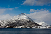 Schneebedeckte Berge an einem Fjord bei Lodingen. Lodingen, Lofoten-Inseln, Nordland, Norwegen.