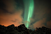 Ein Polarlicht und das Sternbild des Großen Wagens über einem Berggipfel. Andenes, Vesteralen-Inseln, Nordland, Norwegen.