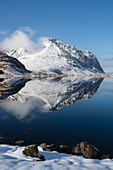 Berge spiegeln sich im ruhigen Wasser eines Sees. Eggum, Lofoten-Inseln, Nordland, Norwegen.