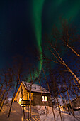 An aurora borealis over Abisko Turiststation cabin, Abisko National Park, Sweden.