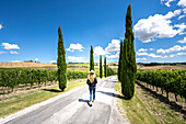 Ein Mädchen zu Fuß unter der Sonne in den Weinbergen Landschaft in der Nähe von Macerata, Region Marken, Italien.