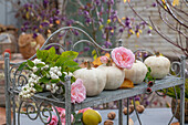 Autumn decoration with ornamental pumpkin, snowberries (Symphoricarpos albus) and rose petals (Rosa) on shelf