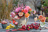 Autumn table decoration made of a bouquet of roses (pink), heather (Calluna vulgaris) and ornamental apple