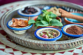 Verschiedene Kräuter und Gewürze für orientalische Gerichte in kleinen Schalen, im Vordergrund Rosenknopsen