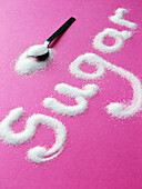 The word sugar spelled out with sugar on a pink background