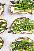 Bread slices with goat cheese, green peas and asparagus