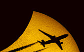 Aeroplane silhouetted against the Sun during partial eclipse