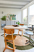 Bright dining room with round table, vintage chairs and natural-colored carpet