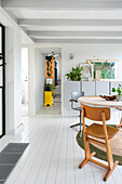 Bright dining room with white floor and Scandinavian design, view into the hallway