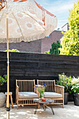 Bamboo armchair and vintage umbrella in front of black-painted wooden wall on the terrace