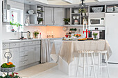 Light grey country kitchen with festively laid table and candle lighting