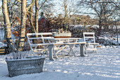 Wooden set with bench and table in the snow-covered garden