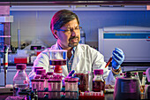 Scientist in laboratory with purple liquid