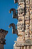 Carved stone Chaac masks with their curling noses on the north building of the Nunnery Quadrangle in the pre-Hispanic Mayan ruins of Uxmal, Mexico.