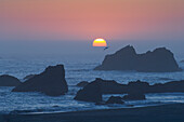 Sonnenuntergang in einer vorgelagerten Nebelbank im Harris Beach State Park, Küste von Oregon.