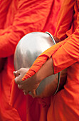 Buddhist monk with bowl during morning procession for offerings of food; Huay Kaew area, Chiang Mai, Thailand.