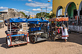 Eine indigene Maya-Frau in einem traditionellen bestickten Huipil steigt vor dem Markt in Acanceh, Yucatan, Mexiko, in ein Motorradtaxi.