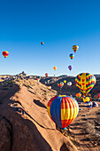 25. jährliche Red Rock Balloon Rally im Red Rock State Park, Gallup, New Mexico. Frühmorgendlicher Massenballonaufstieg mit Church Rock in der Ferne.