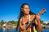 Beautiful local woman playing ukulele in Rangiroa beach, Tuamotu Islands, French Polynesia, South Pacific.