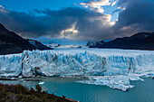 Die zerklüftete Wand des Perito-Moreno-Gletschers und der Lago Argentino im Los-Glaciares-Nationalpark in der Nähe von El Calafate, Argentinien. Ein UNESCO-Weltnaturerbe in der Region Patagonien in Südamerika. Eisberge, die vom kalbenden Eis des Gletschers stammen, schwimmen im See. In der Ferne links ist der Cerro Gardener zu sehen.